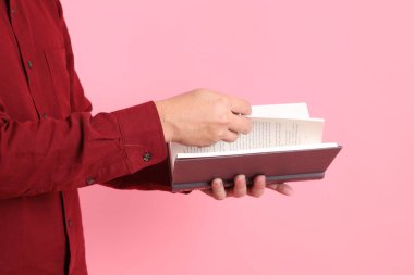 Mutlu Çin Yeni Yılı, resmi ve sıradan kırmızı tişörtlü Asyalı son sınıf öğrencisi pembe arka planda izole edilmiş bir kitabı tutuyor..