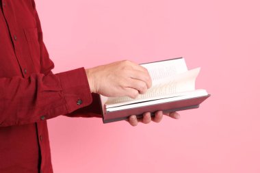 Mutlu Çin Yeni Yılı, resmi ve sıradan kırmızı tişörtlü Asyalı son sınıf öğrencisi pembe arka planda izole edilmiş bir kitabı tutuyor..