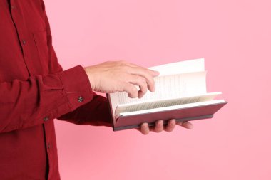 Mutlu Çin Yeni Yılı, resmi ve sıradan kırmızı tişörtlü Asyalı son sınıf öğrencisi pembe arka planda izole edilmiş bir kitabı tutuyor..