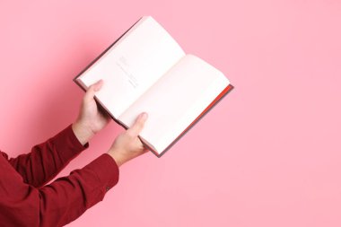 Mutlu Çin Yeni Yılı, resmi ve sıradan kırmızı tişörtlü Asyalı son sınıf öğrencisi pembe arka planda izole edilmiş bir kitabı tutuyor..