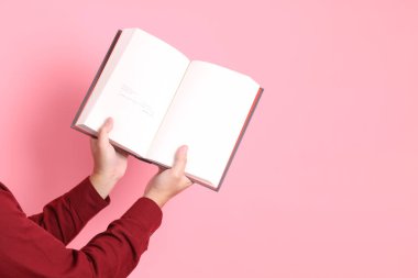 Mutlu Çin Yeni Yılı, resmi ve sıradan kırmızı tişörtlü Asyalı son sınıf öğrencisi pembe arka planda izole edilmiş bir kitabı tutuyor..