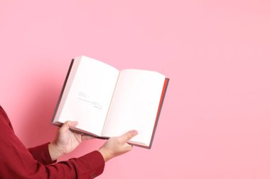 Mutlu Çin Yeni Yılı, resmi ve sıradan kırmızı tişörtlü Asyalı son sınıf öğrencisi pembe arka planda izole edilmiş bir kitabı tutuyor..