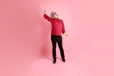 Yeni Çin yılın kutlu olsun. Asya 'nın son sınıf öğrencisi, geleneksel kırmızı Cheongsam Qipao ya da Changshan elbisesi giyiyor. Pembe arka planda soyutlanmış yorgunluk ya da tembellik jesti..