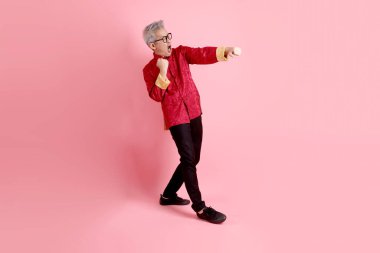 Yeni Çin yılın kutlu olsun. Asya 'nın son sınıf öğrencisi, geleneksel kırmızı Cheongsam Qipao ya da Changshan elbisesi giyiyor. Pembe arka planda izole edilmiş bir dövüş jesti..