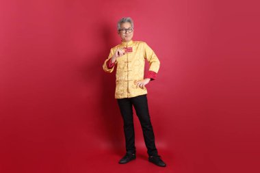 Yeni Çin yılın kutlu olsun. Asya 'lı üst düzey bir Çinli, geleneksel Cheongsam Qipao ya da Changshan elbisesi giyiyor. Kırmızı arka planda kredi kartı var..