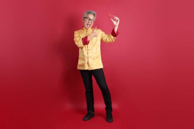 Yeni Çin yılın kutlu olsun. Asya 'lı üst düzey bir Çinli, geleneksel Cheongsam Qipao ya da Changshan elbisesi giyiyor. Kırmızı arka planda kredi kartı var..