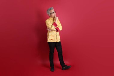 Yeni Çin yılın kutlu olsun. Asya 'nın son sınıf öğrencisi altın rengi Cheongsam Qipao ya da Changshan elbisesi giyiyor. Kırmızı arka planda izole edilmiş bir düşünce jesti..