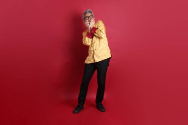 Yeni Çin yılın kutlu olsun. Asya 'nın son sınıf öğrencisi, geleneksel Cheongsam Qipao ya da Changshan elbisesi giyen, sürpriz yapan ve kırmızı arka planda izole edilmiş etkileyici bir Çinli..