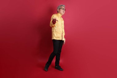 Yeni Çin yılın kutlu olsun. Asya 'nın son sınıf öğrencisi altın rengi Cheongsam Qipao ya da Changshan elbisesi giyiyor. Kırmızı arka planda izole edilmiş korku işareti var..