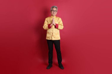 Yeni Çin yılın kutlu olsun. Asya 'nın son sınıf öğrencisi altın rengi Cheongsam Qipao ya da Changshan elbisesi giyiyor. Kırmızı arka planda karşılama işareti var..