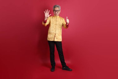 Yeni Çin yılın kutlu olsun. Asya 'nın son sınıf öğrencisi altın rengi Cheongsam Qipao ya da Changshan elbisesi giyiyor. Kırmızı arkaplanda sayım numarası ya da hesaplama işareti var..