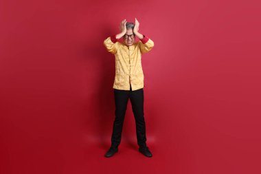 Yeni Çin yılın kutlu olsun. Asya 'nın son sınıf öğrencisi altın rengi Cheongsam Qipao ya da Changshan elbisesi giyiyor. Baş ağrısı ya da kırmızı arka planda izole edilmiş stres işareti var..