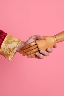 Çin yeni yılı. Asya 'nın son sınıf öğrencisi, geleneksel kırmızı Cheongsam Qipao ya da Changshan elbisesi giyiyor. Manken eli, pembe arka planda insan eli ile tokalaşıyor..