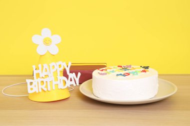 Doğum günü pastası, mutlu yıllar mesajı, parti şapkası, sarı arka planda izole edilmiş hediye kutusu, mutlu yıllar konsepti. Aile