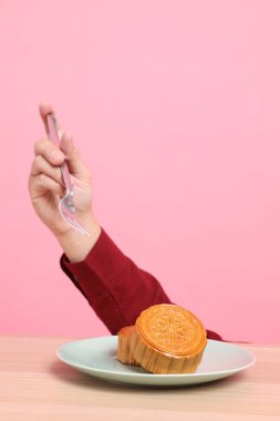 Geleneksel Çin tatlı ay çöreği yemek için çatal ya da pembe arka planda Çin pastası. Çin Geleneksel Sonbahar Festivali, Ay Festivali.