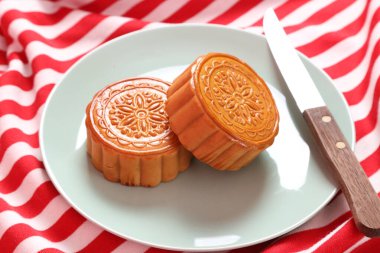 Geleneksel Çin tatlı ay çöreği ya da pembe arka planda izole edilmiş kırmızı çizgili masa örtüsü üzerine Çin pastası. Çin Geleneksel Sonbahar Festivali, Ay Festivali.