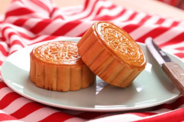 Geleneksel Çin tatlı ay çöreği ya da pembe arka planda izole edilmiş kırmızı çizgili masa örtüsü üzerine Çin pastası. Çin Geleneksel Sonbahar Festivali, Ay Festivali.