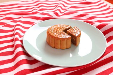 Geleneksel Çin tatlı ay çöreği ya da pembe arka planda izole edilmiş kırmızı çizgili masa örtüsü üzerine Çin pastası. Çin Geleneksel Sonbahar Festivali, Ay Festivali.