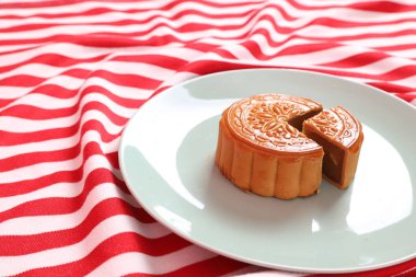 Geleneksel Çin tatlı ay çöreği ya da pembe arka planda izole edilmiş kırmızı çizgili masa örtüsü üzerine Çin pastası. Çin Geleneksel Sonbahar Festivali, Ay Festivali.