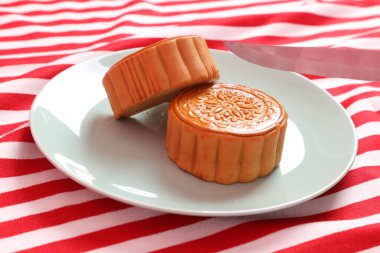 Geleneksel Çin tatlı ay çöreği ya da pembe arka planda izole edilmiş kırmızı çizgili masa örtüsü üzerinde Çin pastası kesmeye hazır olun. Çin Geleneksel Sonbahar Festivali, Ay Festivali.