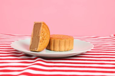 Geleneksel Çin tatlı ay çöreği ya da pembe arka planda izole edilmiş kırmızı çizgili masa örtüsü üzerine Çin pastası. Çin Geleneksel Sonbahar Festivali, Ay Festivali.