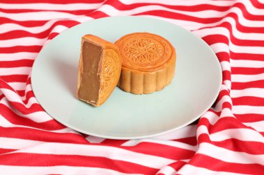 Geleneksel Çin tatlı ay çöreği ya da pembe arka planda izole edilmiş kırmızı çizgili masa örtüsü üzerine Çin pastası. Çin Geleneksel Sonbahar Festivali, Ay Festivali.