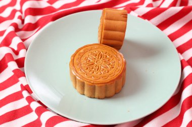 Geleneksel Çin tatlı ay çöreği ya da pembe arka planda izole edilmiş kırmızı çizgili masa örtüsü üzerine Çin pastası. Çin Geleneksel Sonbahar Festivali, Ay Festivali.