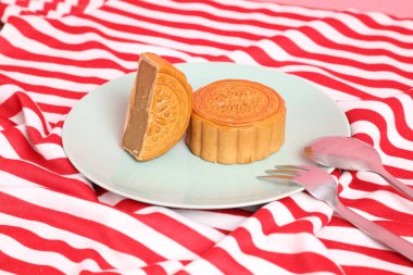 Geleneksel Çin tatlı ay çöreği ya da pembe arka planda izole edilmiş kırmızı çizgili masa örtüsü üzerine Çin pastası. Çin Geleneksel Sonbahar Festivali, Ay Festivali.