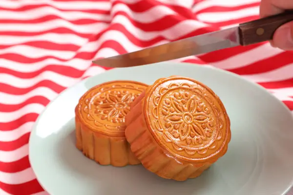 Geleneksel Çin tatlı ay çöreği ya da pembe arka planda izole edilmiş kırmızı çizgili masa örtüsü üzerinde Çin pastası kesmeye hazır olun. Çin Geleneksel Sonbahar Festivali, Ay Festivali.