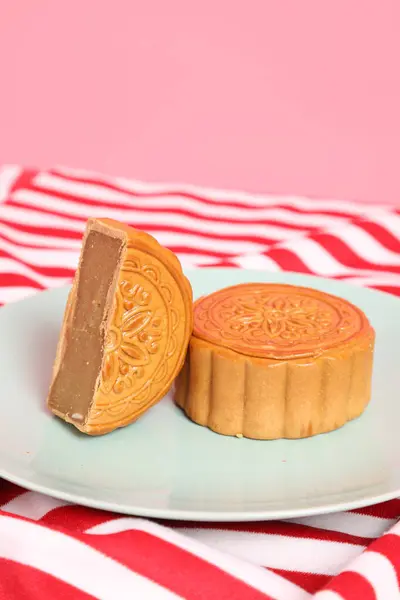 Geleneksel Çin tatlı ay çöreği ya da pembe arka planda izole edilmiş kırmızı çizgili masa örtüsü üzerine Çin pastası. Çin Geleneksel Sonbahar Festivali, Ay Festivali.