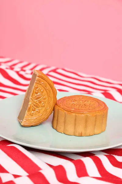Geleneksel Çin tatlı ay çöreği ya da pembe arka planda izole edilmiş kırmızı çizgili masa örtüsü üzerine Çin pastası. Çin Geleneksel Sonbahar Festivali, Ay Festivali.