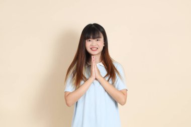 Açık mavi polo tişörtlü, beyaz şortlu, bej arka planda selamlaşan orta boy bir Asyalı kadın resmi. Üniversite öğrencisi, Gen Z