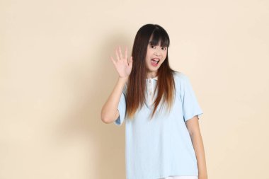 Açık mavi polo tişörtlü, beyaz şortlu, bej arka planda selamlaşan orta boy bir Asyalı kadın resmi. Üniversite öğrencisi, Gen Z