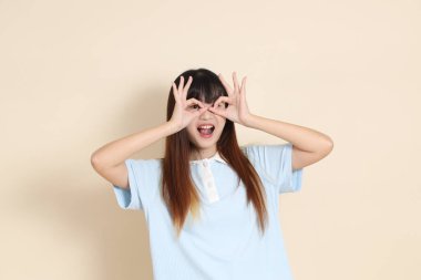 Açık mavi polo tişörtlü genç bir Asyalı kadın ve beyaz şortlu, baş parmakları havada, tamam mı? Üniversite öğrencisi, Gen Z, Summer