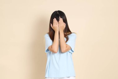 Açık mavi polo tişörtlü, beyaz şortlu, bej arka planda gözleri olan genç Asyalı bir kadın. Üniversite öğrencisi, Gen Z, Summer