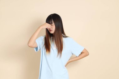 Açık mavi polo tişörtlü, beyaz şortlu, bej arka planda kusmuk olan genç bir Asyalı kadın. Üniversite öğrencisi, Gen Z, Summer