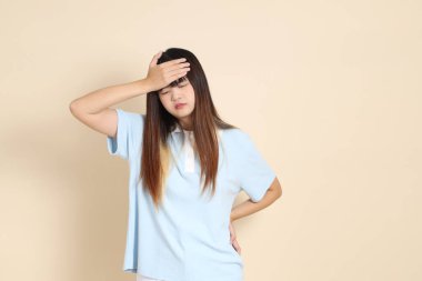 Açık mavi polo tişörtlü, beyaz şortlu, bej arka planda kusmuk olan genç bir Asyalı kadın. Üniversite öğrencisi, Gen Z, Summer