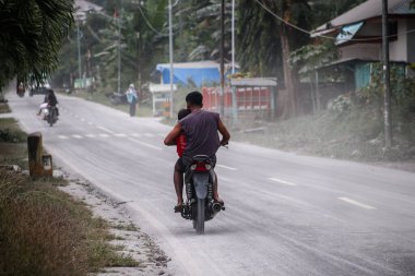 Boru, Larantuka, Endonezya-5 Haziran 2024: Motosiklet sürücüleri Lewotobi 2024 Yanardağı 'nın patlaması nedeniyle volkanik küllerle dolu Boru-Hokeng-Larantuka otobanından geçtiler.