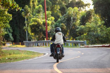 Ormanda motosiklet süren genç adam.