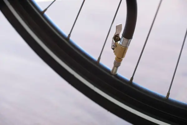 Close-up view of a bicycle pump hose with a valve clamp, connected to a bicycle tire valve. Context: inflating bicycle tires, tire pressure, tire inflation, getting ready, bicycle safety, service, bike tour, puncture, precaution, monitoring.