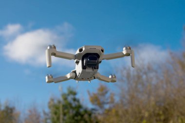 Sonbahar ağaçlarının önünde uçan bir dron güzel bir bokeh teslim ediyor. İnsansız hava aracına bir ND filtresi eklendi. Projenizi, sonbahar yeşilliklerinin önünde hazır bir ND filtresi bulunan DJI Mini2 insansız hava aracının zorlu bir görüntüsüyle yükseltin.