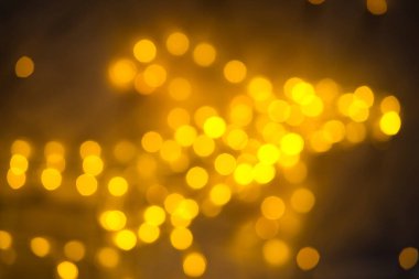 Çerçevenin üzerinde asimetrik olarak sıralanmış orta büyüklükteki non-agonların yer aldığı bu bokeh görüntüsüyle büyüleyici ışık oyunlarını keşfedin. Işıklar, parlak sarı ve altın renginde, karanlık bir arkaplanda dans ederek, görsel olarak dinamik bir kompozisyon oluşturur. P