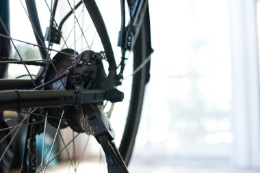 E-motorun arka tekerleğinin yakından görüntüsü, fren diski ve kickstand eklemlerini içeriyor. Metin için uygun olan sağdaki parlak arkaplan.