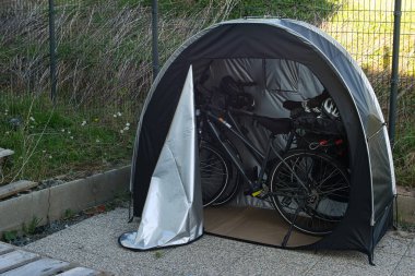 Bisiklet çadırı, açık havada iki tane E-motorsiklet barındırıyor. İçerik: bisiklet deposu, bisiklet güvenliği, park yeri, bisiklet turu, bisiklet koruması, gezi, bisiklet macerası, kamp.