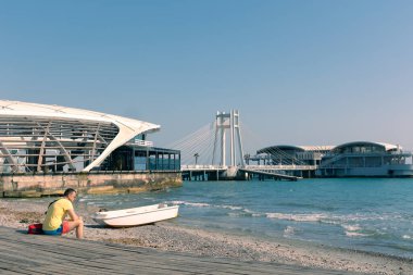 Durres, Arnavutluk - 13 Nisan 2024 - Durres gezinti güvertesinin bir adamla birlikte ahşap bir platformda oturduğu fotoğraf