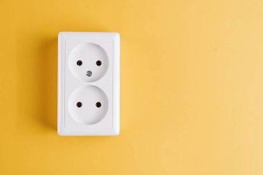 Sarı arka planda beyaz çift prizli. Elektrik aydınlatma kavramı