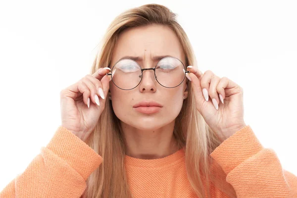 金发年轻女子戴着眼镜 斜视着被白色背景隔离的相机 视觉问题概念 — 图库照片