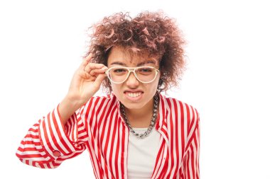 Beyaz arka planda izole edilmiş kameraya bakarken gözlerini kısarak bakan beyaz kıvırcık saçlı genç bir kadın. Görüş sorunları kavramı