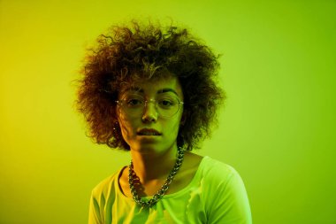 Stüdyonun arka planında izole edilmiş neon ışıklı bukleli havalı Kazak model kız portresi.