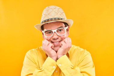 Sarı arka planda izole edilmiş, şapkalı, gülümseyen şişman bir adamın portresi. Seyahat konsepti.